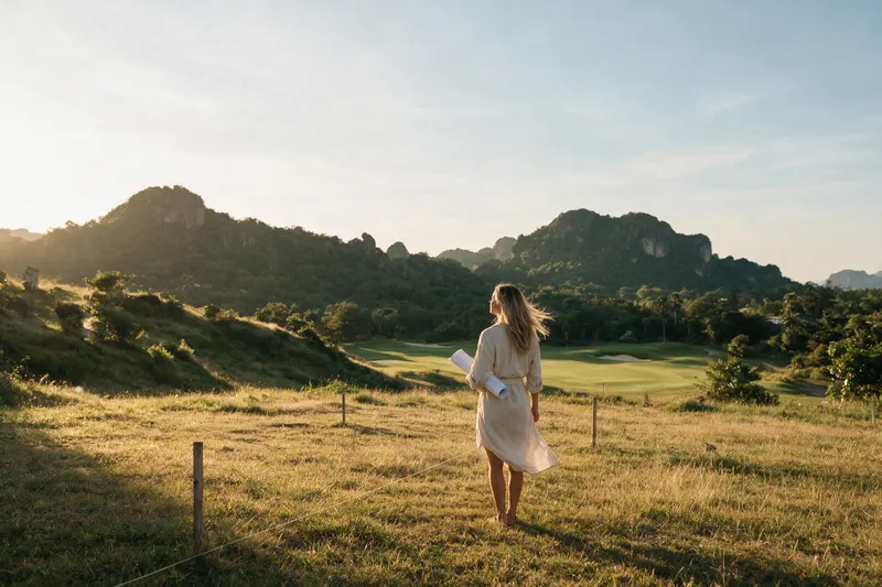 Jessica walking the land with the plans, the hills behind